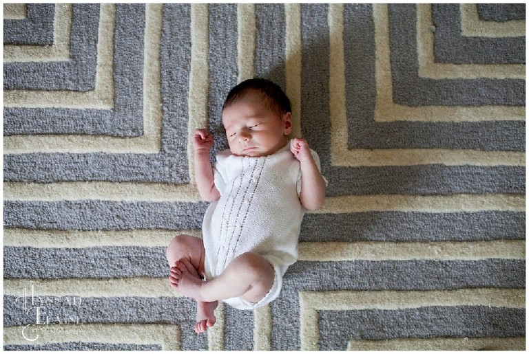 newborn boy lays on symmetrical gray rug 