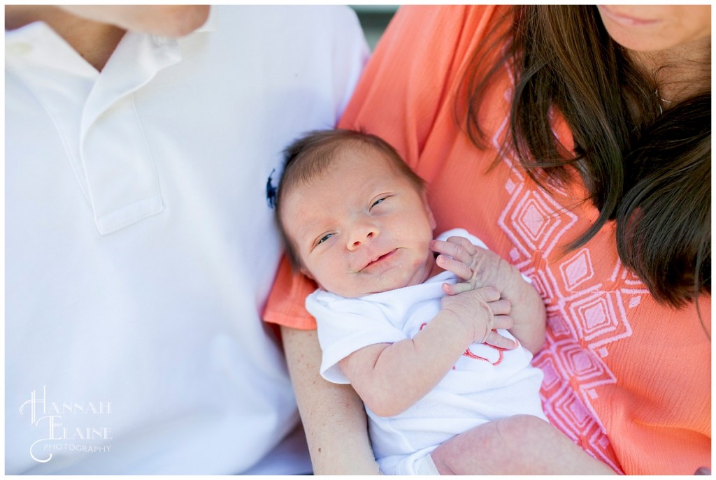 close up of smiling newborn in parent's arms