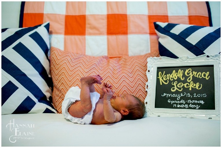 newborn on couch next to personalized chalk board art