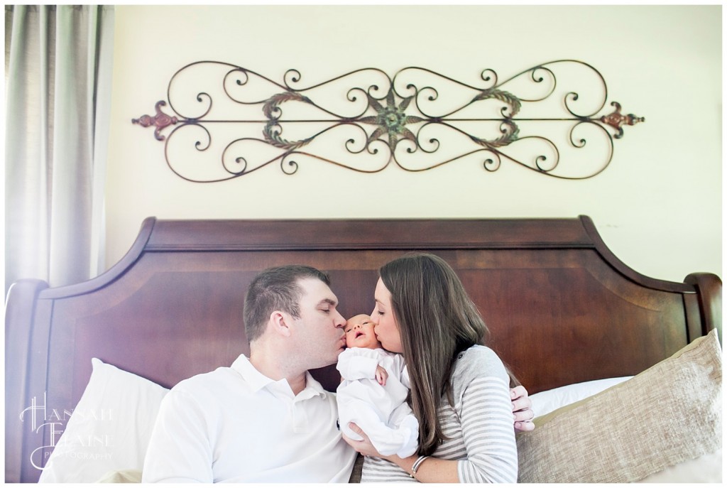 mom and dad kiss each cheek of their new baby's face