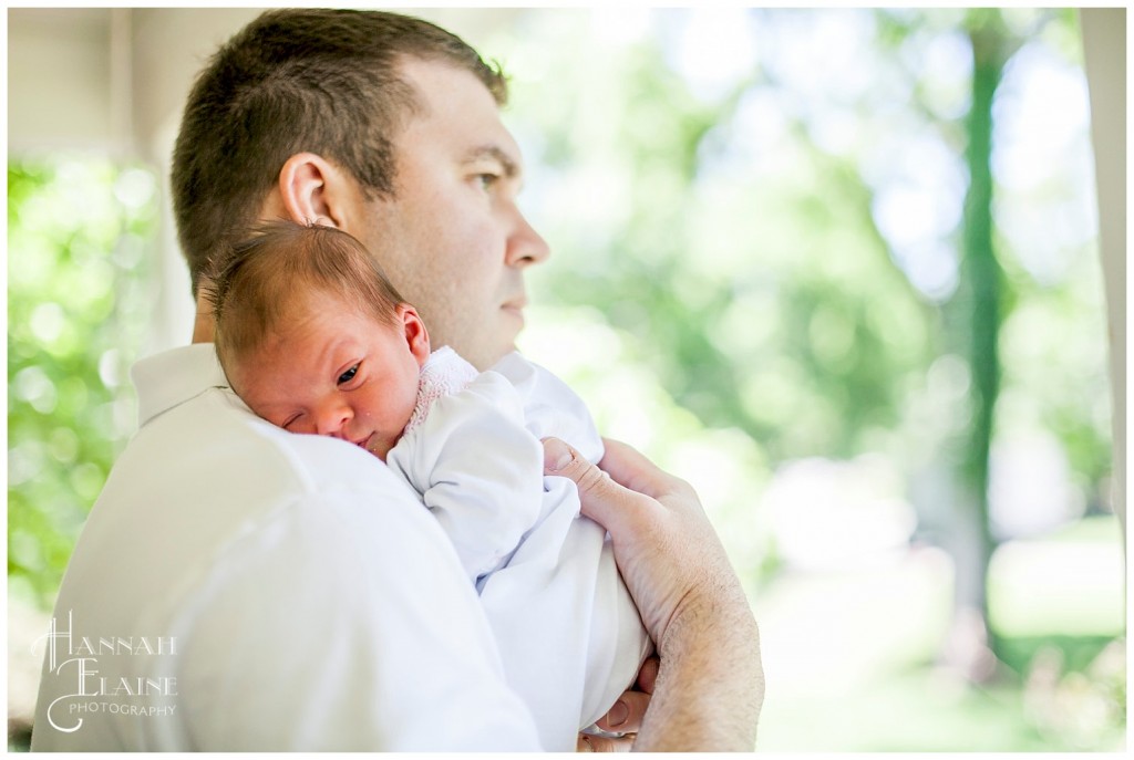 daddy snuggles his newborn daughter over his shoulder