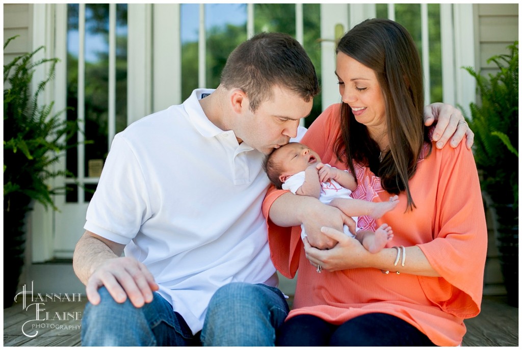 daddy kisses his new daughter's head as momma holds her