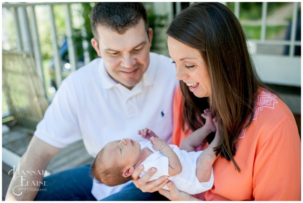 candid shot of mom and dad laughing with their new baby