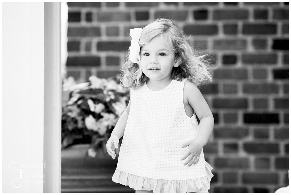 black and white picture of little girl in front of brick