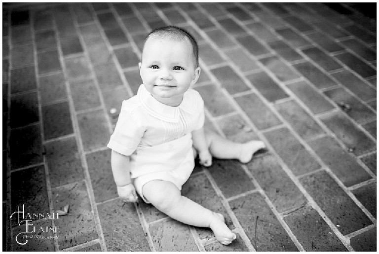 black and white photo of little boy sitting on brick path