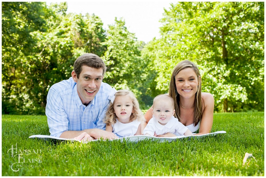 family on blanket in the grass say cheese