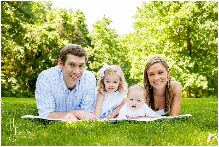 family of four lay on a blanket in the park