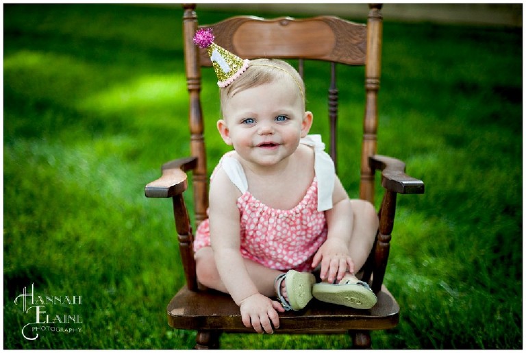 one year old in vintage rocker with party hat on 