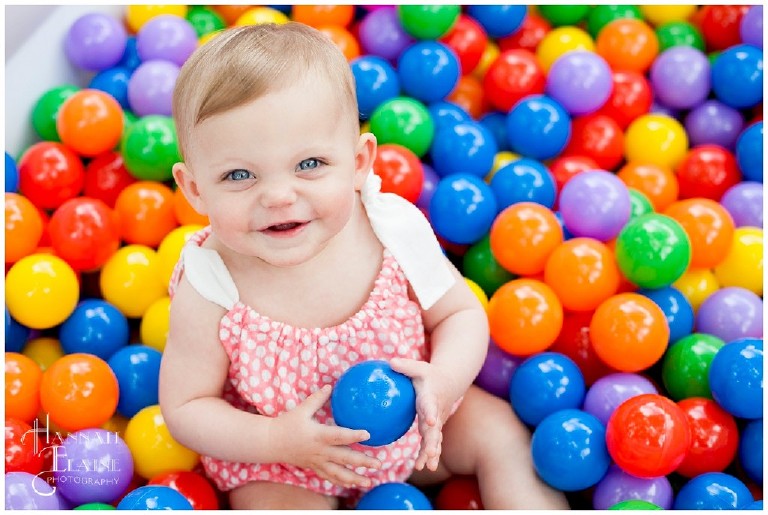 little blue eyed girl sits in her ball pit