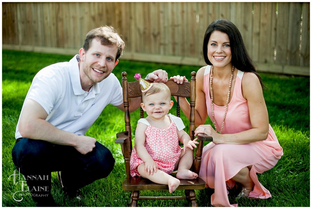 mother and father sit next to their daughter in vintage kid rocker