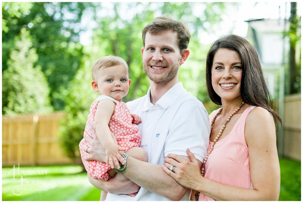 mommy, daughter and daddy take family pictures in the backyard