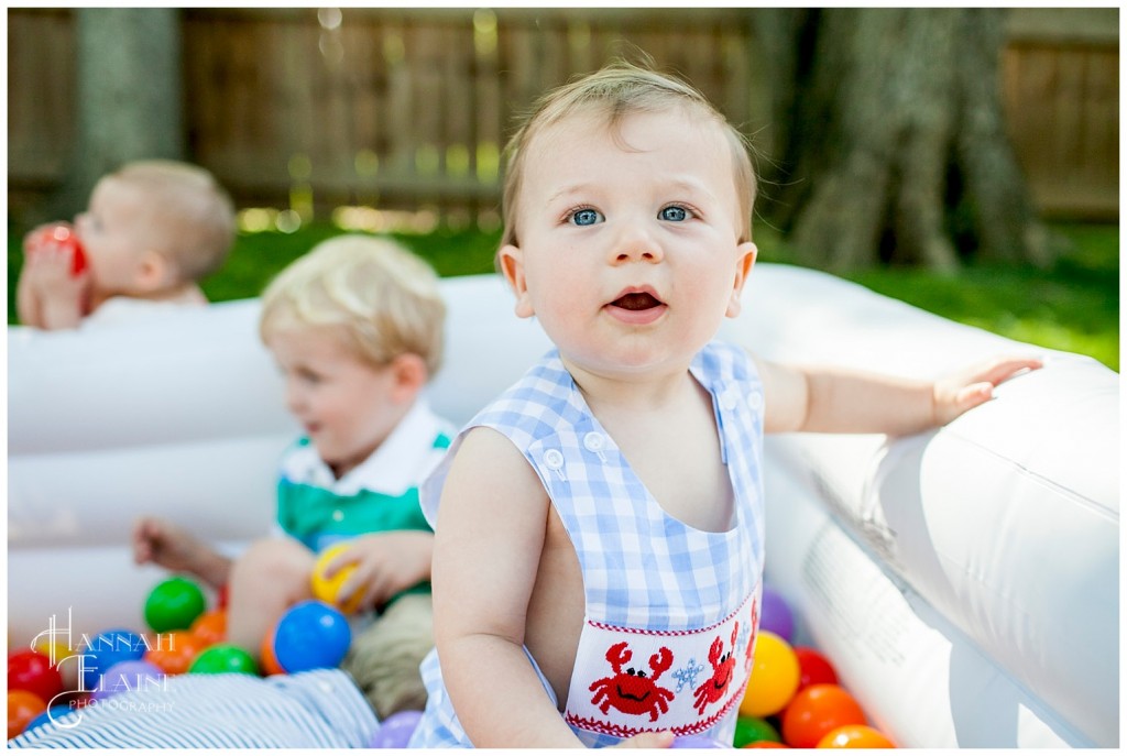 little boy in lobster jumper plays in the ball pit