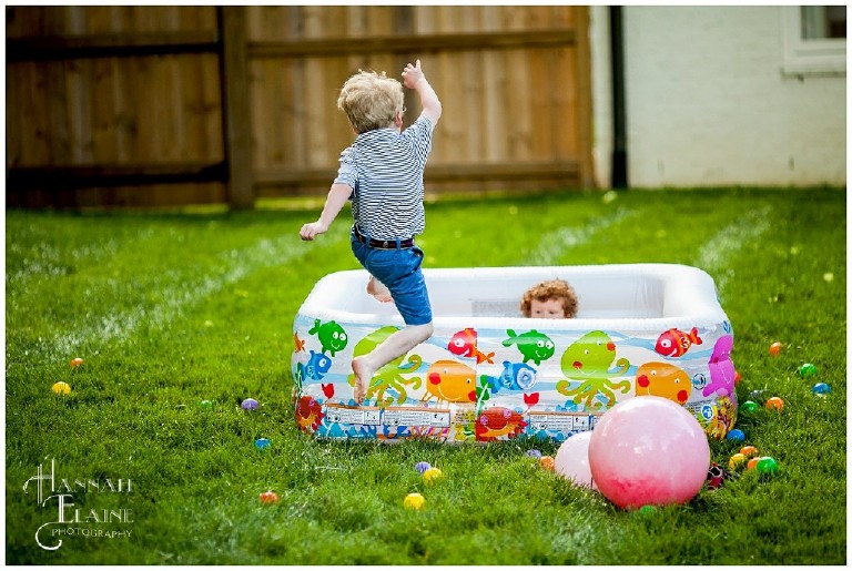 little boy runs and jumps into kiddie pool turned ball pit