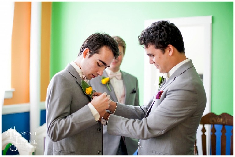 groom helps fasten a boutonierre on his lapel