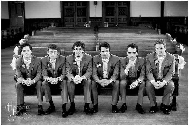 groomsmen sit in a pew for a photo