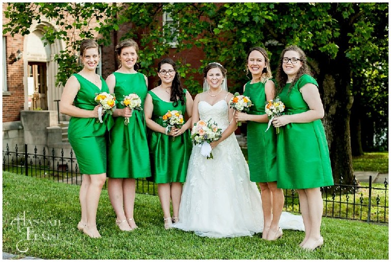 girls in emerald green bridesmaids dresses stand with the bride