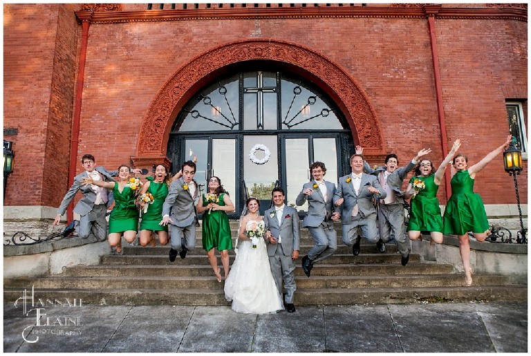 bridal party jumps off the front steps of the church