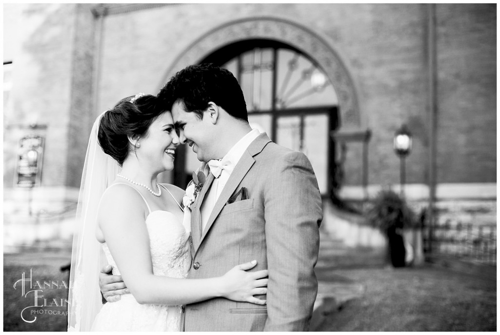 husband and wife pose in front of wedding ceremony chapel