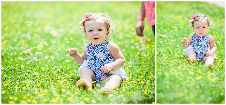 one year old girl sits in a grassy field of yellow flowers