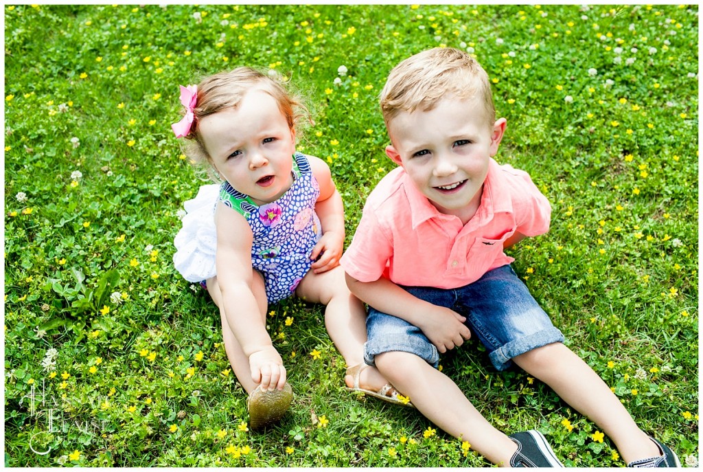 two siblings sit together in the grass