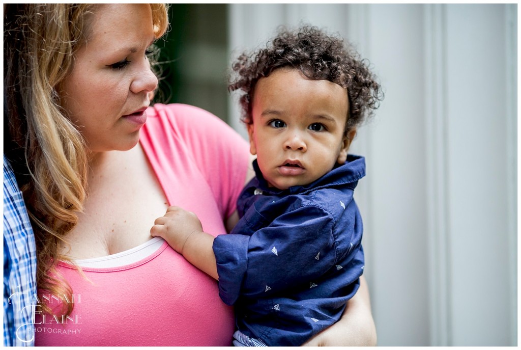 theo holds on to his mommy and stares into the camera