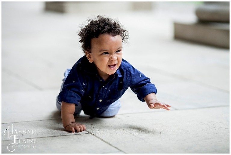 little boy makes a scrunched up face as he crawls across the pavers