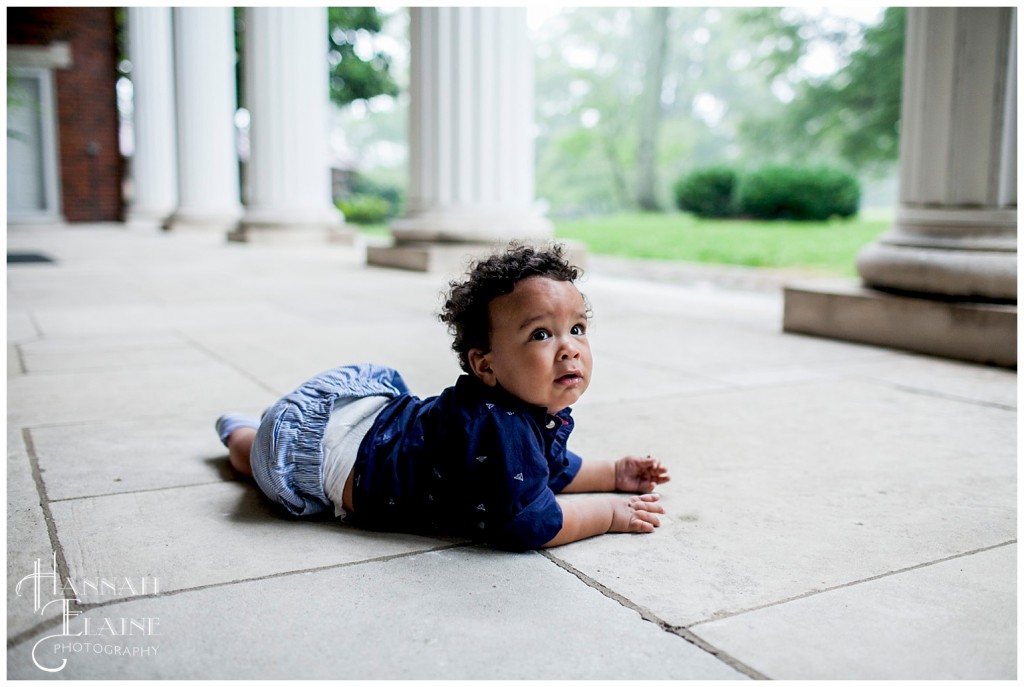 little boy in blue army crawls across the porch