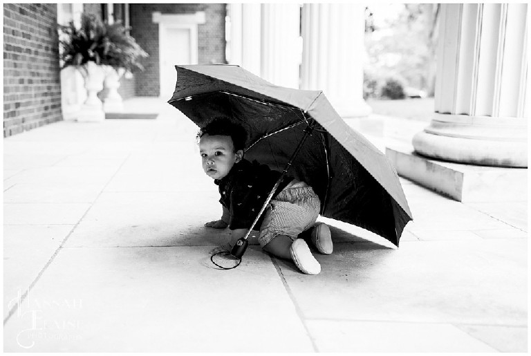 toddler crawls under an umbrella on a rainy day