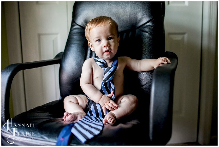 boy wearing daddy's tie around his neck in office chair
