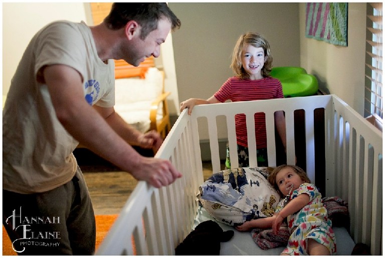 dad and brother wake up little girl in her crib