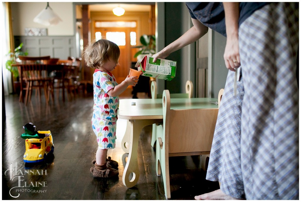 mom helps daughter pour some milk into a cup