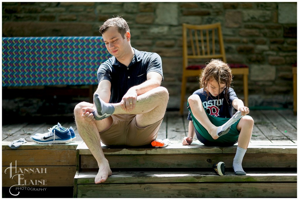 dad and son simultaneously pull off wet socks