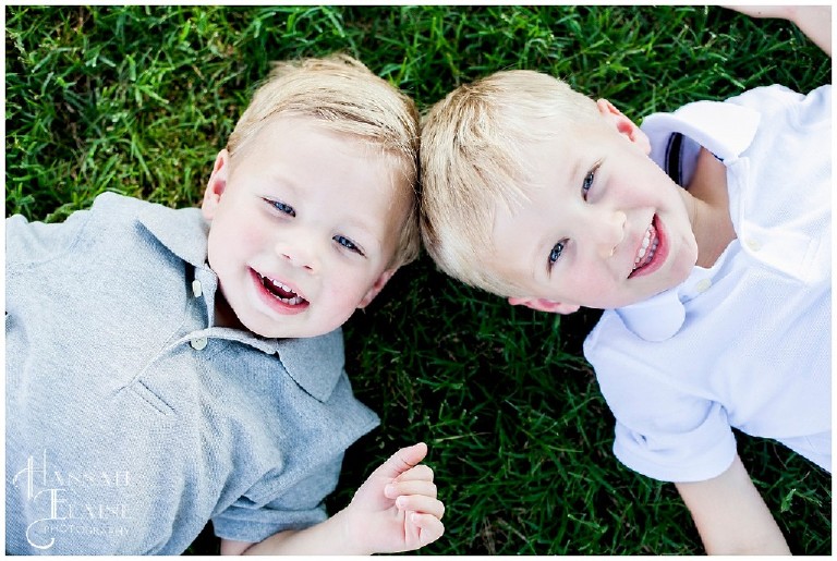 two blond boys lay head to head in the grass