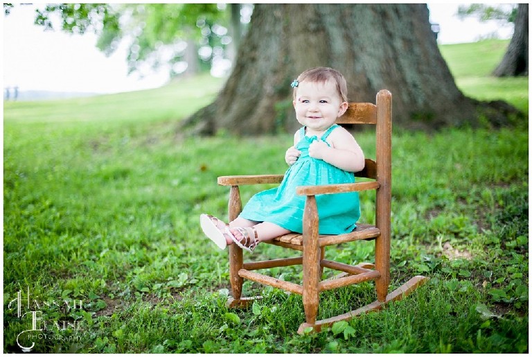 little girl in green dress giggles in her vintage kids rocking chair