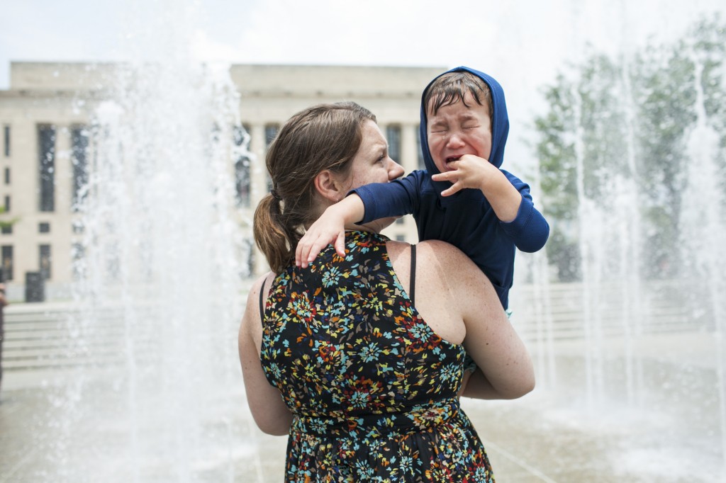 little boy cries as mom tries to persuade him into the water