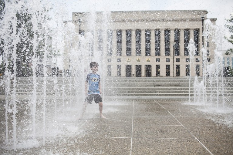 boy stands in the row of water fountains