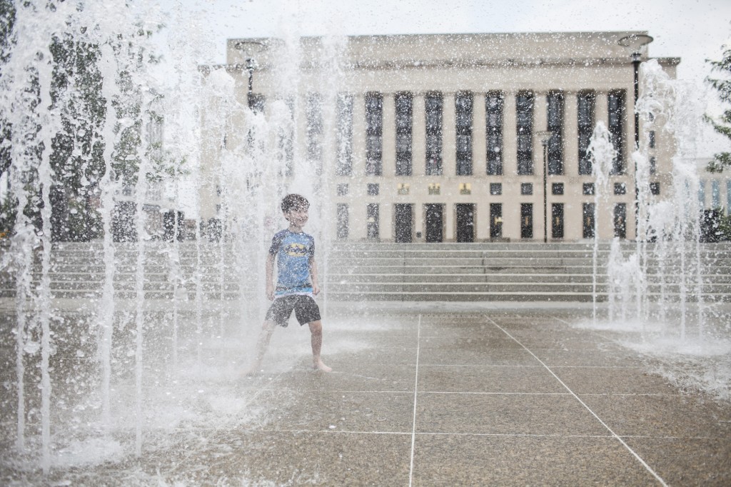 boy stands in the row of water fountains