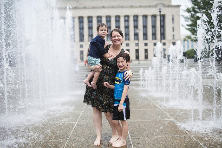 family stands amongst the fountains in front of the courthouse downtown