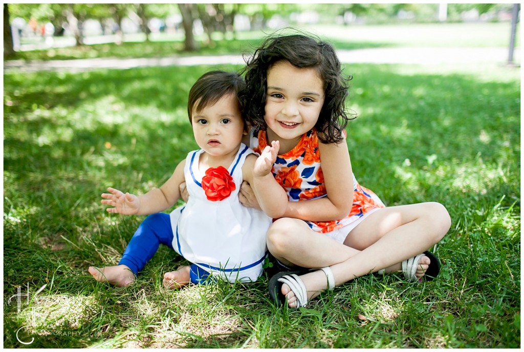 sisters sit in the grass in the park