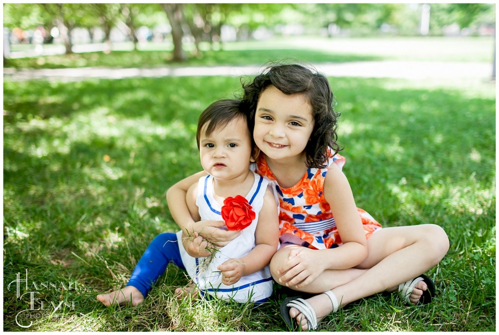 two young girls hug together in the grass at bicentennial