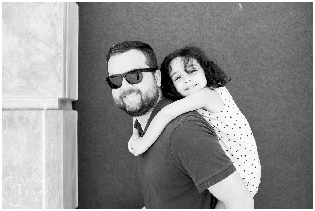 black and white image of girl on daddy's back