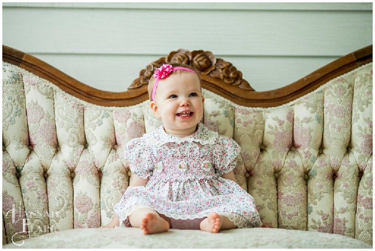 one year old girl with pink bow on vintage couch