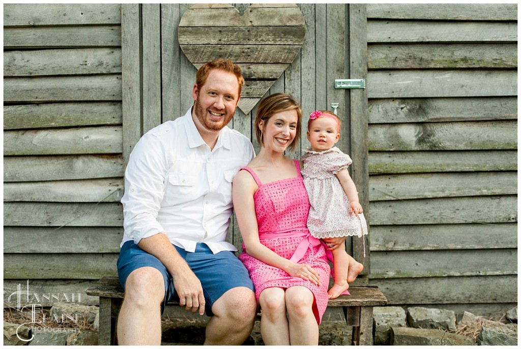 family sits for a photo in front of rustic barn