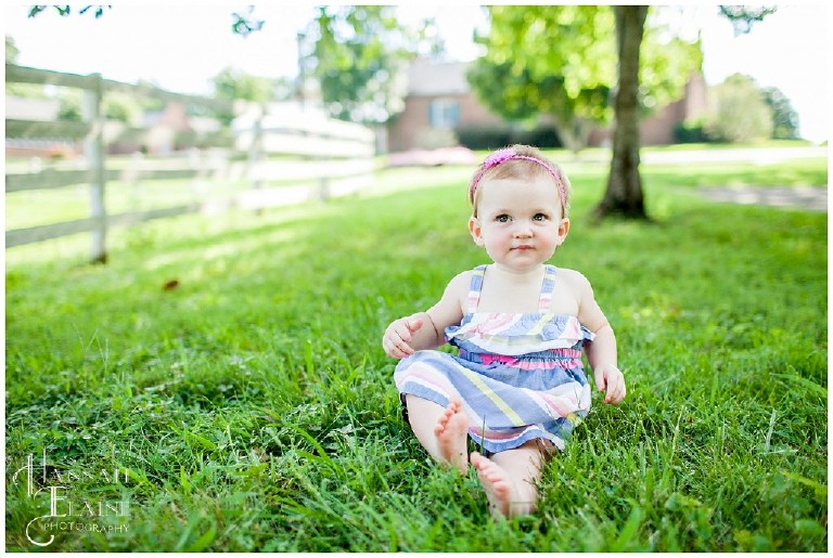 little girl isn't sure how she feels about sitting in the grass