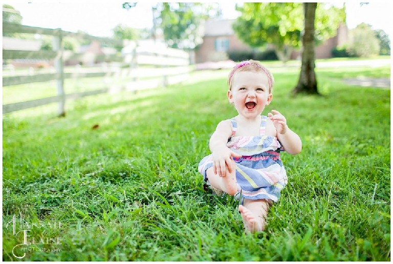 toddler laughs at the grass tickling her feet