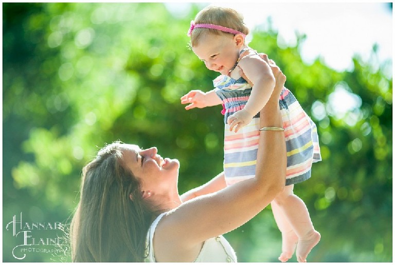 mom hoists baby girl up in the air