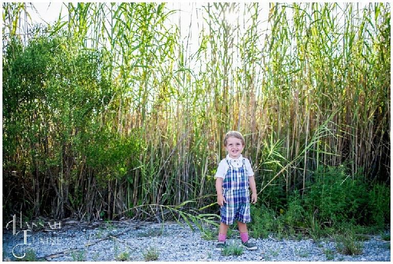 toddler in jumper playing in the tall grass on the beach