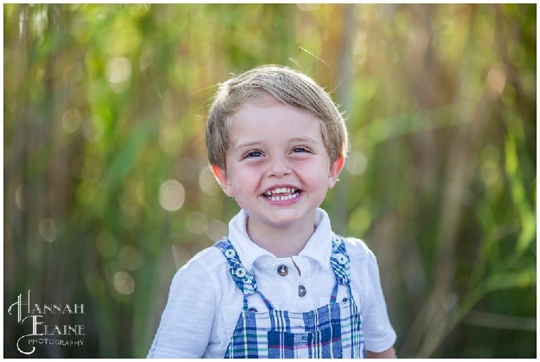 closeup of boy in plaid jumper smiling in the sunset