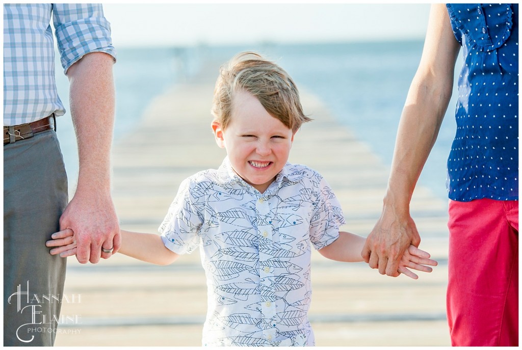 little boy holding parent's hands on the dockside in mobile bay