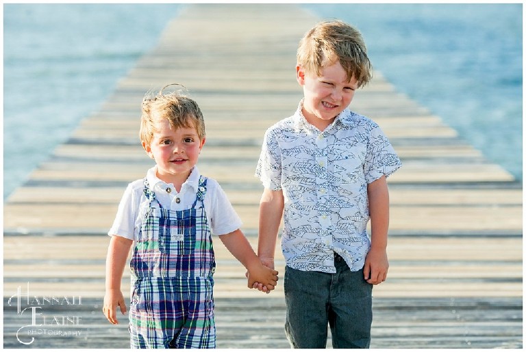 two little boys hold hands on the dock at mobile bay
